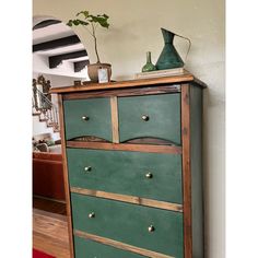 a green painted dresser with brass handles and knobs on the bottom drawer, in a living room