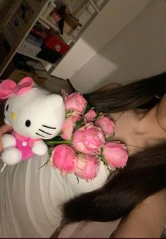 a woman holding a hello kitty stuffed animal with pink roses