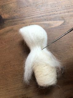 a pair of scissors and some white wool on a wooden table