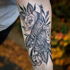 a woman's arm with flowers and scissors on it