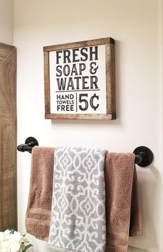 two towels hanging on a towel rack in a bathroom with a sign above it that says fresh soap and water hand free