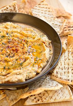 a black bowl filled with hummus and crackers