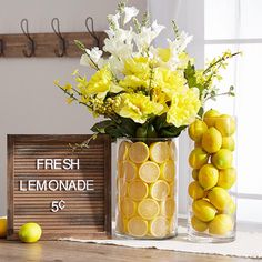 two vases filled with lemons and flowers next to a sign