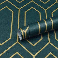 a green and gold patterned wallpaper with a roll of tape laying on top of it