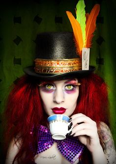 a woman with red hair wearing a top hat and holding a tea cup in her hands