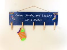 a blue sign hanging from clothes pins on a white wall with a pair of socks