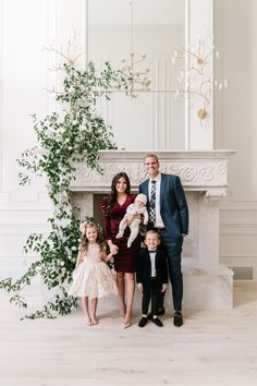 a family posing for a photo in front of a fireplace with greenery on the mantle