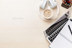 an open laptop computer sitting on top of a desk next to headphones and pens