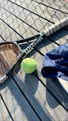 a tennis racquet and ball on a wooden surface with a towel next to it