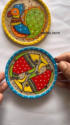 two hand painted plates sitting next to each other