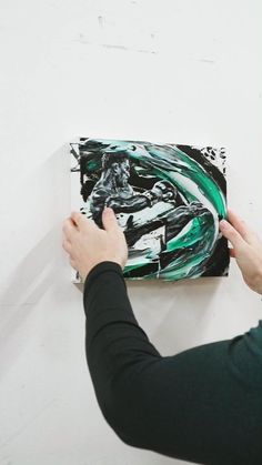 a person is painting on the wall with black and green paint