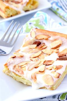 a piece of cake with almonds on it sitting on a plate next to a fork