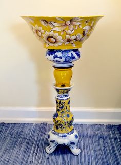 a yellow vase sitting on top of a blue and white floor next to a wall