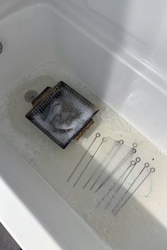 a bathtub filled with lots of tools and water in it's drain hole