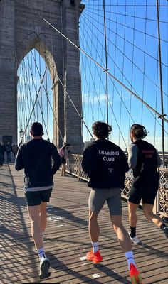 three men running across the brooklyn bridge