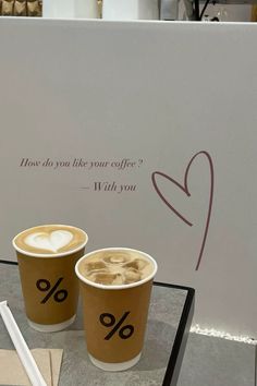 two cups of coffee sitting on top of a table next to a sign that says, how do you like your coffee?