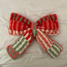 a red and green knitted bow laying on top of a bed