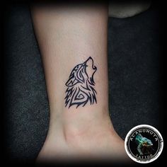 a tattoo on the foot of a person with a wolf head in black ink,