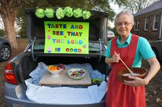 an older woman holding a bowl and chopsticks in front of her car trunk