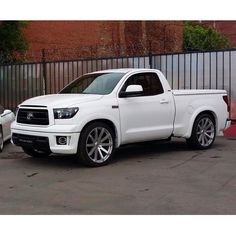 two white trucks parked next to each other in front of a fenced off area