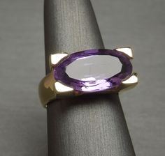 Mid Century Euro Style Circa 1960 Constructed completely of 14KT Yellow Gold Containing 1 Central Genuine Earth-Mined Oval cut Natural Amethyst weighing approximately 11.50 carats Amethyst measuring approximately 9.2mm x 17.7mm Secured in 4 Heavy Squared Prongs NOTE: Refer to photos -- 1 surface scratch.. Priced accordingly.. Simply a characteristic of vintage estate pieces this age.. *Amethyst is the birthstone for those born in the month of February.. Top section of ring measuring approximatel Luxury Amethyst Oval Cabochon Ring, Antique Oval Amethyst Multi-stone Ring, Vintage Amethyst Jewelry With Polished Finish, Vintage Multi-stone Amethyst Ring In 14k Gold, Luxury Formal Amethyst Ring, Oval Cabochon, Euro Style, Statement Ring, Oval Cut, Heart Ring