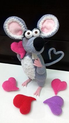 a crocheted toy mouse with hearts around it