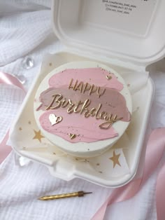 a birthday cake with pink frosting and gold writing on it in a white box