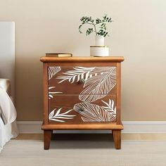 a white plant is sitting on top of a wooden cabinet next to a small bed