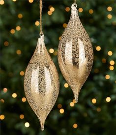 two gold ornaments hanging from a christmas tree