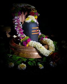 a hat with flowers around it sitting on top of a wooden box in the dark