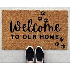 someone standing in front of a welcome mat that says welcome to our home with paw prints