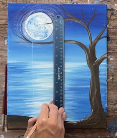 someone is painting a tree with a ruler in front of it and the moon behind them