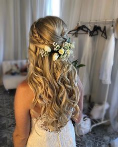 a woman with long hair and flowers in her hair is looking at another woman's wedding dress