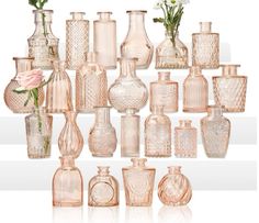 a collection of pink glass vases with flowers in them