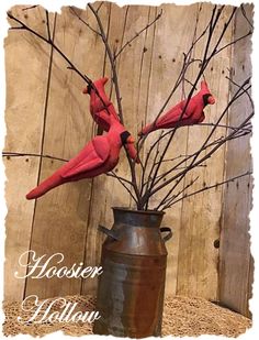 two red birds are perched on branches in a vase with another bird sitting on the branch