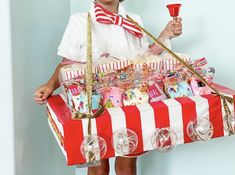 a woman holding a red and white box filled with candy