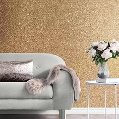 a living room with gold glitter wallpaper and a gray couch in the foreground