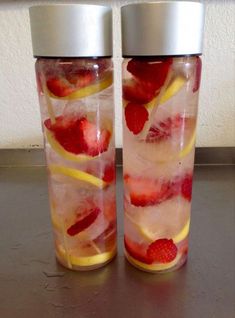 two cups with strawberries and lemons in them sitting on a table next to each other