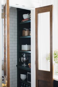 an open pantry door in a kitchen with dishes and utensils on the shelves