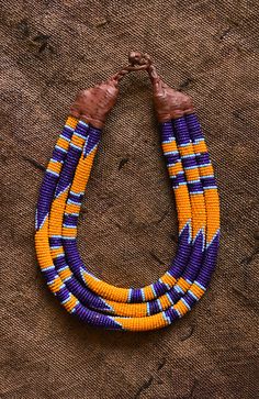 This Beaded Statement Collar is a classic and stylish African tribal necklace crafted using traditional tribal techniques. Featuring eco-friendly, colorful beads in a tribal pattern, this necklace is perfect for making a statement and will be a beautiful addition to any wardrobe. 9 inches Traditional Purple Beaded Necklace With Round Beads, Traditional Brown Beaded Necklace With Colorful Beads, Traditional Brown Beaded Necklace With Multicolored Beads, Traditional Multicolor Wooden Beaded Necklaces, Traditional Handmade Purple Beaded Necklaces, Traditional Handmade Purple Necklaces, Traditional Multicolor Wooden Beaded Necklace, Statement Jewelry Necklace, Statement Collar