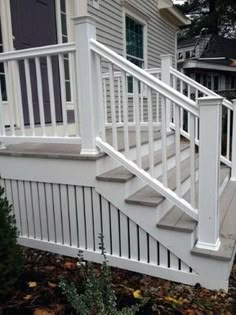 a white railing and hand rail on a deck in front of a house with trees