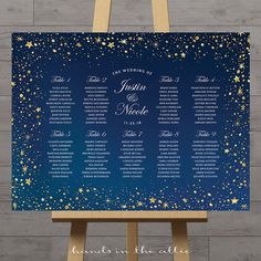 a blue and gold wedding seating chart on an easel with stars in the sky