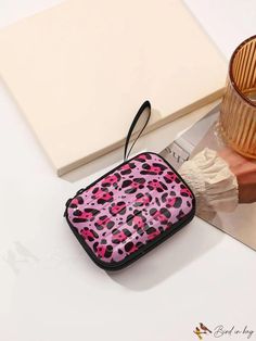 a pink and black animal print purse sitting on top of a table next to a candle