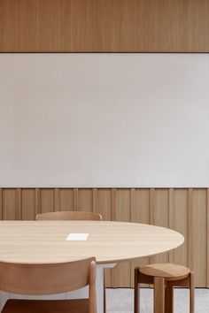 a table and two stools in front of a white board with wood paneling