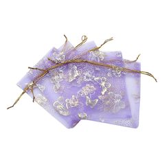 four lavender colored napkins with gold foil flowers on them and twigs sticking out of the top