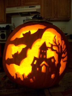 a pumpkin carved to look like a house with bats on it