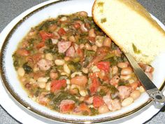 a bowl filled with beans and meat next to a piece of bread