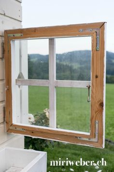 an open window on the side of a building with grass in the background and a field behind it