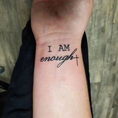 i am enough tattoo on the wrist with cross and words in cursive font