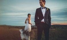 a bride and groom standing in the middle of an open field at sunset or dawn